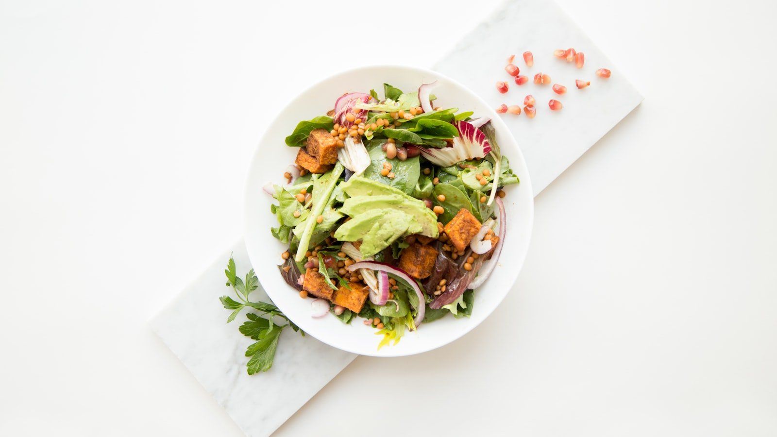 Glass food containers filled with colorful freshly prepped healthy meals lined up on a kitchen counter.