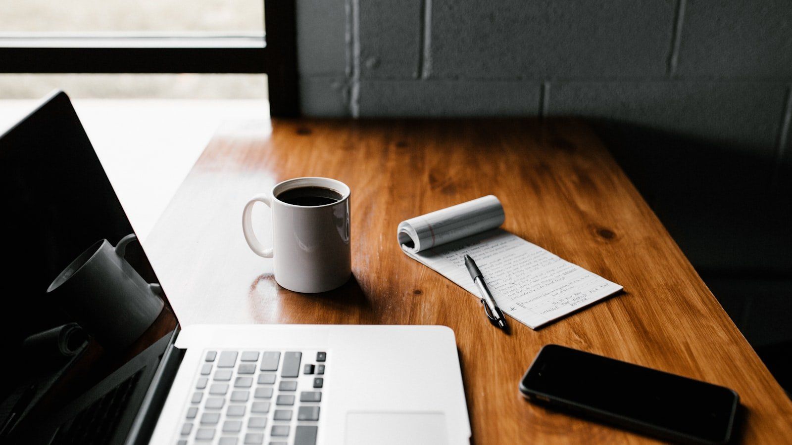 A clean home office desk with a notebook, coffee mug, and organized financial planning sheets.